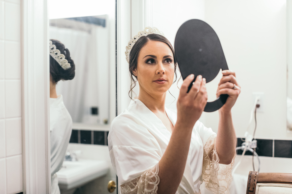 Bride holding up a mirror.