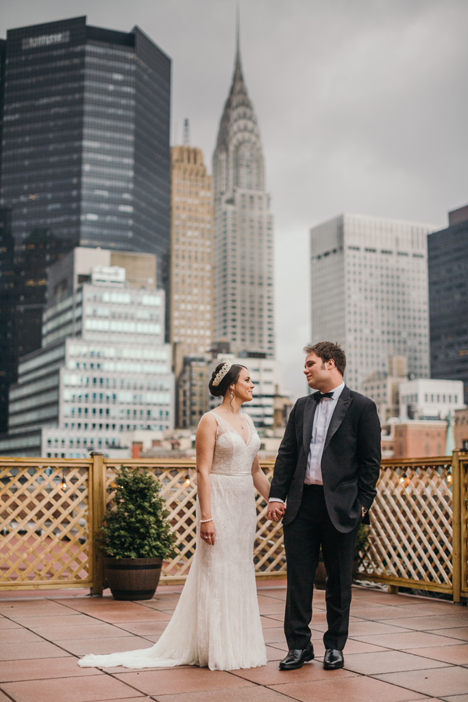Bride and groom holding hands on Manhattan rooftop.