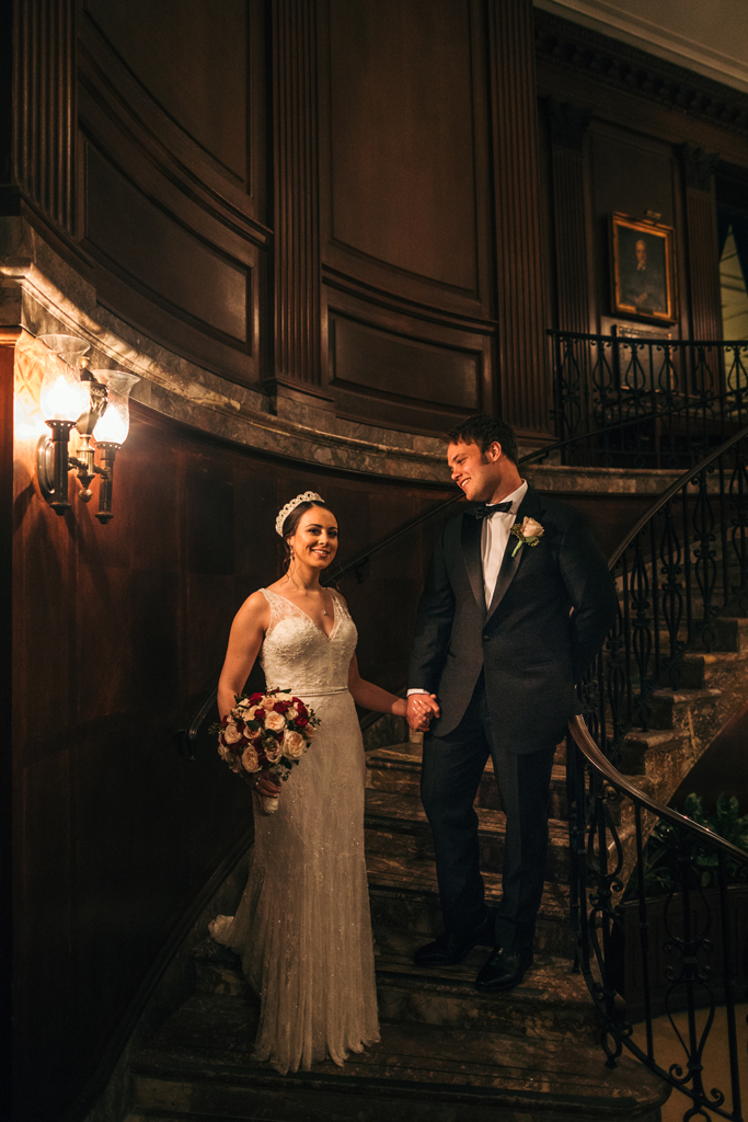 Bride and groom on elegant staircase.